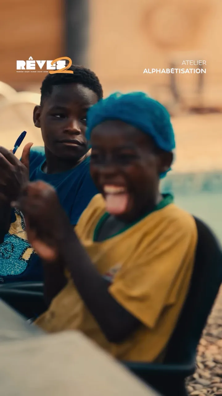 A child in a yellow shirt bursts out laughing during a RÊVES 2 workshop.
