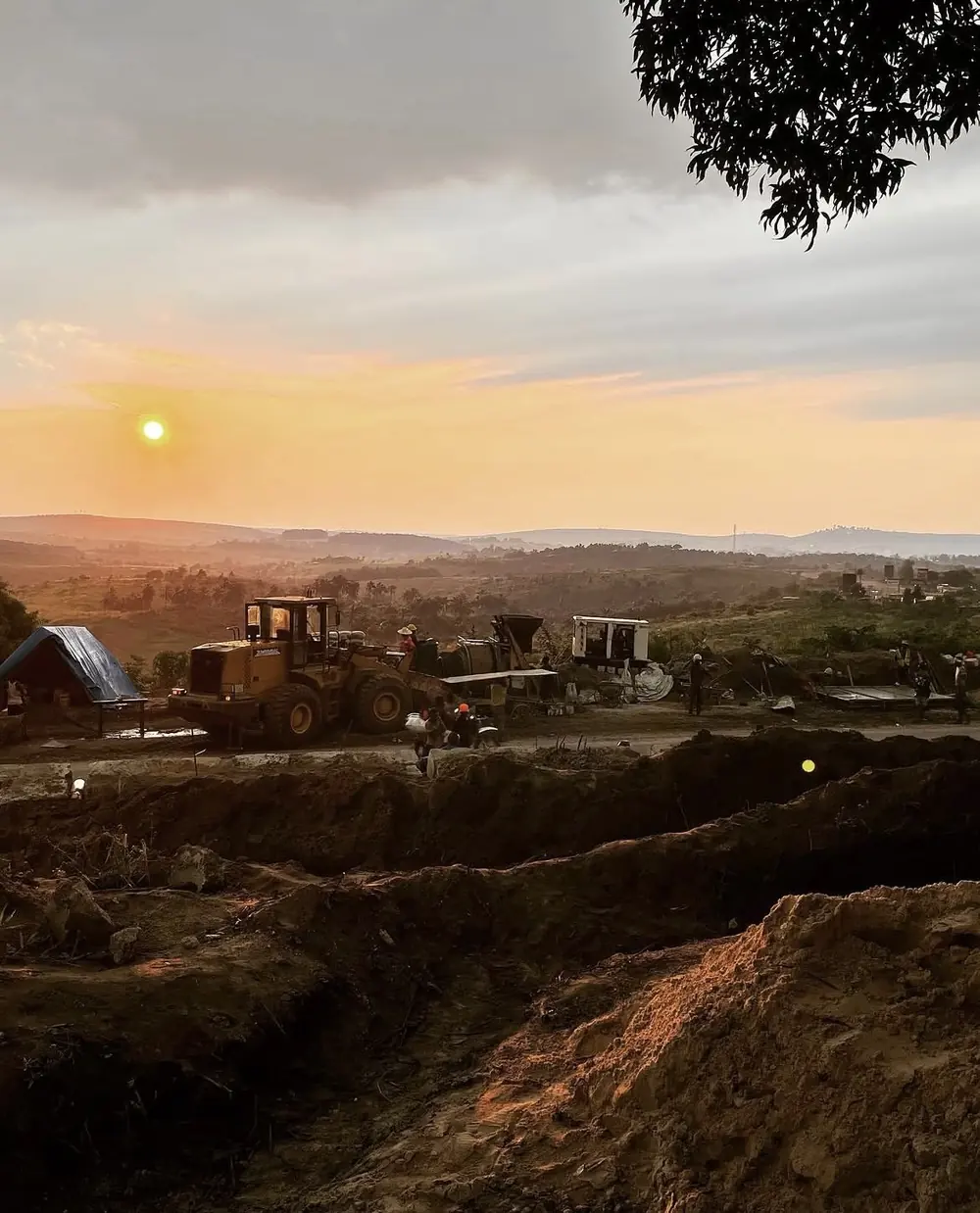 Des engins au travail sur le terrain, au coucher du soleil.