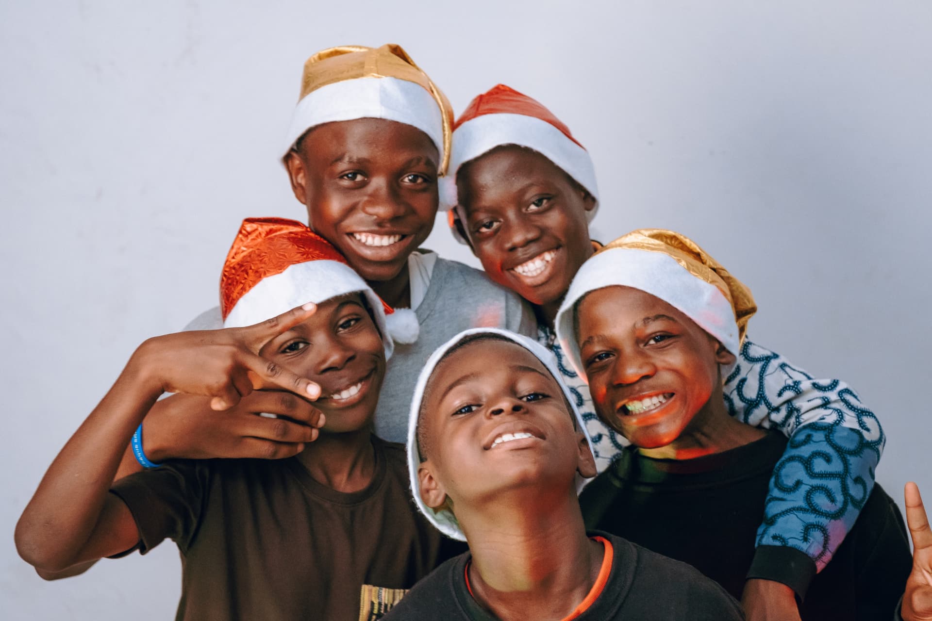 Cinq One Love Boys en bonnet de Noël, serrés les uns contre les autres et souriants.